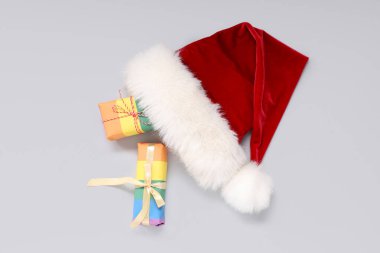Açık arkaplanda Noel Baba şapkası olan renkli hediye kutuları. LGBT kavramı