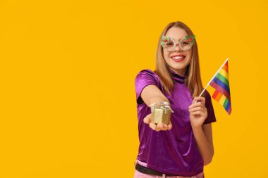 LGBT bayrağı ve sarı arka planda Noel hediyesi olan genç bir kadın.