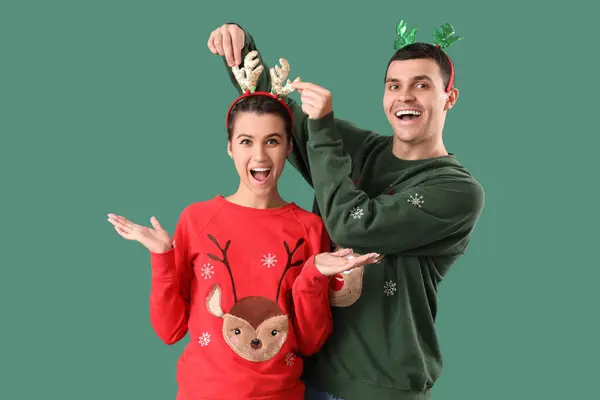 Young Couple Christmas Sweaters Reindeer Horns Green Background — Stock Photo, Image