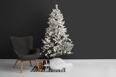 Karanlık duvarın yanında rahat koltuğu olan güzel bir Noel ağacı. Tasarım için pankart