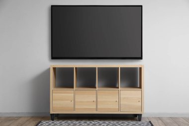 Odanın ahşap tezgahının yanındaki ışık duvarında asılı modern akıllı TV seti