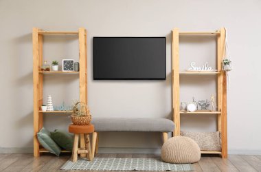 Ahşap rafların yanında asılı modern akıllı TV seti ve odada bank