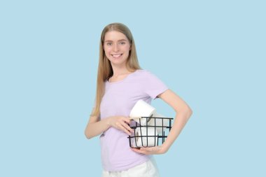 Elinde tuvalet kağıdı ruloları olan sepet tutan genç bir kadın.