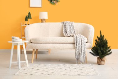 Beyaz kanepesi ve küçük Noel ağacı olan şenlikli bir oturma odası.