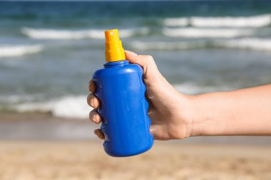 Otelde güneş kremi şişesiyle kadın eli.