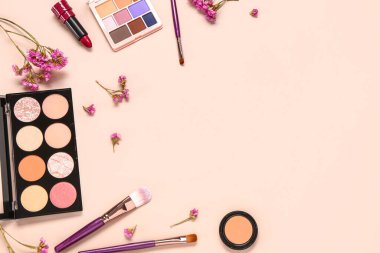 Farklı makyaj ürünleri ve pembe arka planda güzel çiçekler olan kompozisyon