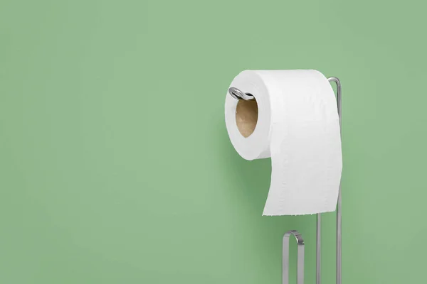 Holder with toilet paper roll near color wall, closeup