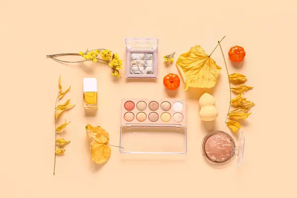 Autumn composition with makeup products on beige background