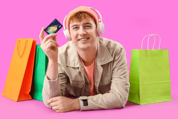 Jongeman Met Credit Card Boodschappentassen Liggend Paarse Achtergrond — Stockfoto