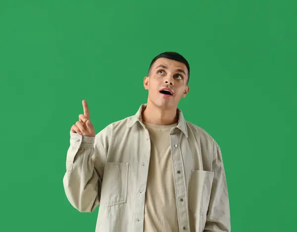 Junger Mann Zeigt Auf Etwas Auf Grünem Hintergrund — Stockfoto