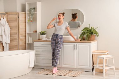 Banyoda dişlerini fırçalayan güzel genç bir kadın.