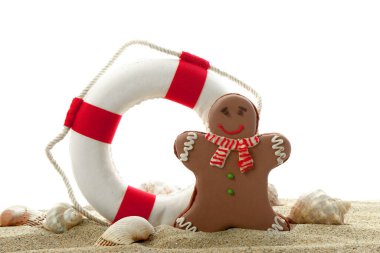 Yaşam şamandıralı lezzetli zencefilli kurabiye ve beyaz arka planda kumlu deniz kabukları.