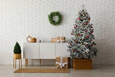 Güzel Noel ağacı, şifoniyeri ve hediye kutuları beyaz tuğla duvarın yanında.