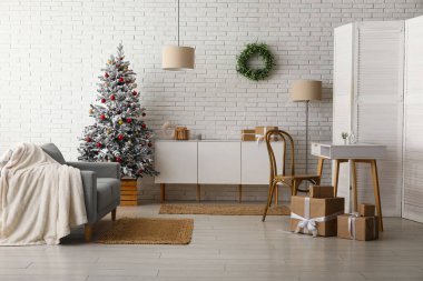 Dekore edilmiş Noel ağacı, şifonyer ve kanepesi olan oturma odasının içinde.