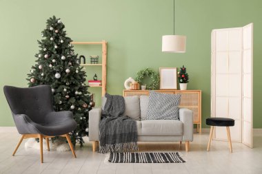 Dekore edilmiş Noel ağacı, koltuk ve kanepesi olan oturma odasının içinde.