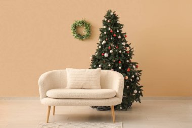 Bej duvarın yanında kanepesi olan güzel bir Noel ağacı.
