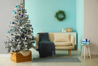 Dekore edilmiş Noel ağacı, şifonyer ve kanepesi olan oturma odasının içinde.