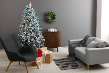 Dekore edilmiş Noel ağacı, koltuk ve kanepesi olan oturma odasının içinde.