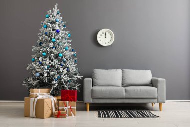 Güzel Noel ağacı hediye kutuları ve gri duvarın yanındaki kanepe