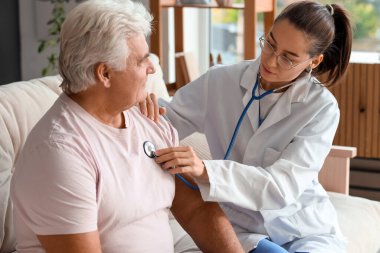 Genç hemşire evde steteskoplu yaşlı adamı duyuyor.