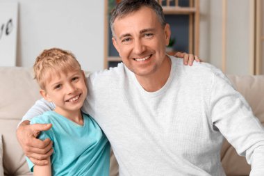 Yetişkin bir doktor, küçük oğlunu evinde kucaklıyor.