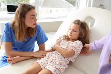 Annesi ve doktoruyla klinikte ateşini ölçen hasta küçük bir kız.