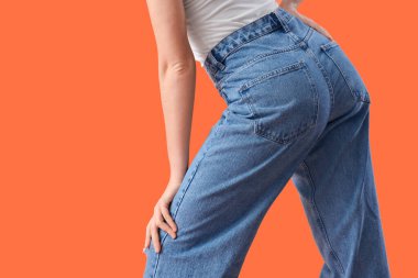 Turuncu arka planda şık kotlu genç bayan, yakın plan.