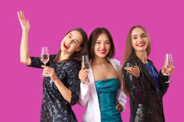 Mor arka planda şampanyası olan güzel genç kadınlar. Yeni yıl kutlaması