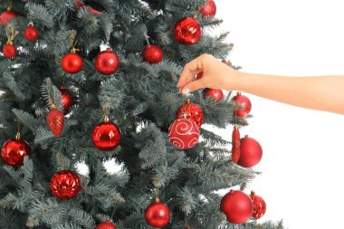 Beyaz arka planda kırmızı toplarla Noel ağacını süsleyen kadın, yakın plan