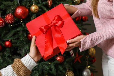 Evde Noel ağacının yanında hediyeli genç çift, yakın plan.