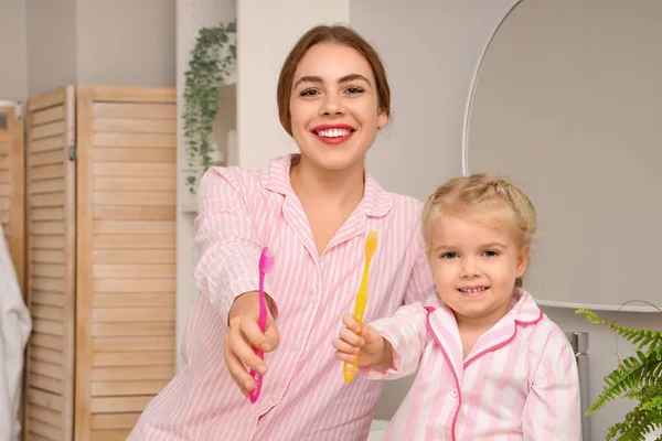 若い母親と彼女の小さな娘は バスルームに歯ブラシを持っています — ストック写真