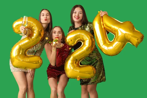 Beautiful young women with champagne and figure 2024 on green background. New Year celebration