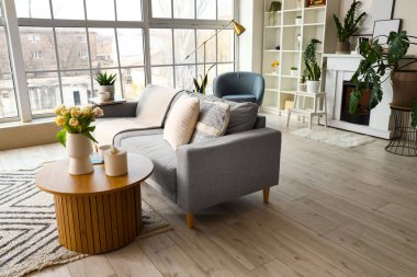 Parlak oturma odasının içinde gri kanepe ve kahve masası var.