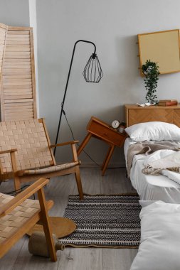 Yatak ve komodinli dağınık bir yatak odası.