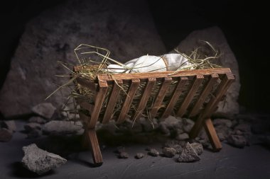 Bebekli ahır, karanlık masada saman ve taşlar