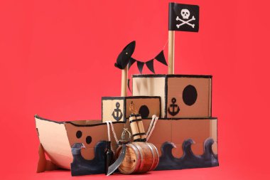 Kırmızı zemin üzerinde patlayıcı bulunan korsan karton gemi.