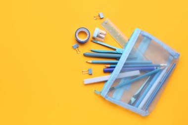 Turuncu arka planda farklı kırtasiye malzemesi olan kalem kutusu