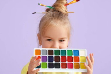 Leylak arkaplanda boyaları olan sevimli küçük bir kız, yakın plan.