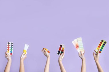 Leylak arka planında sanatçı malzemeleri olan kadın eller.