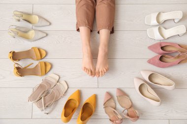 Aydınlık zeminde farklı ayakkabıları olan kadın bacakları.