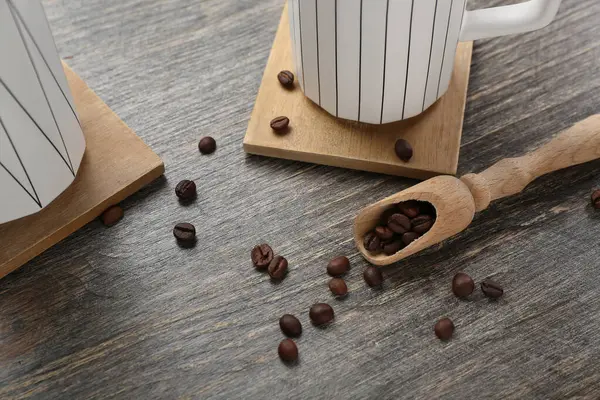 Drink coasters with cups and coffee beans on wooden table