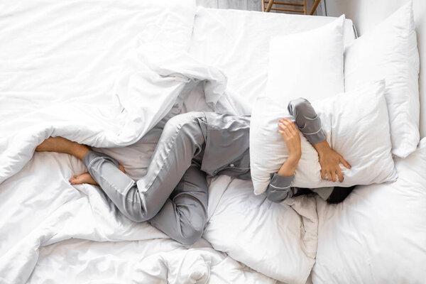 Молодая женщина спит в спальне, вид сверху