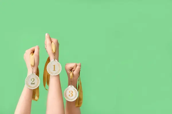 Female hands with medals on green background