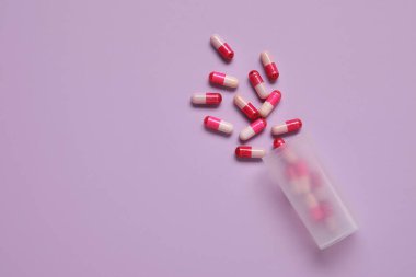 Leylak arka planında dağınık haplarla dolu kavanoz.