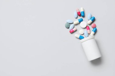 Jar with different scattered pills on grey background clipart