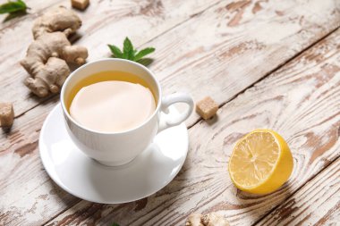 Beyaz ahşap zemin üzerinde limonlu ve naneli zencefil çayı.