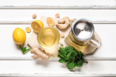 Beyaz arka planda limon ve nane aromalı bir bardak zencefil çayı.