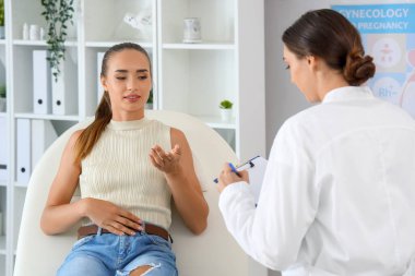 Kadın jinekolog, klinikte bir hastayla doğum kontrolü hakkında konuşuyor.