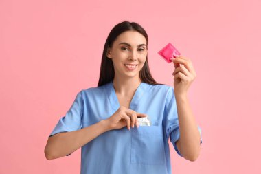 Pembe arka planda prezervatifleri olan kadın jinekolog.