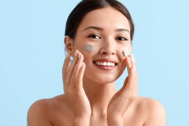 Güzel Asyalı kadın mavi arka plana yüz maskesi takıyor.